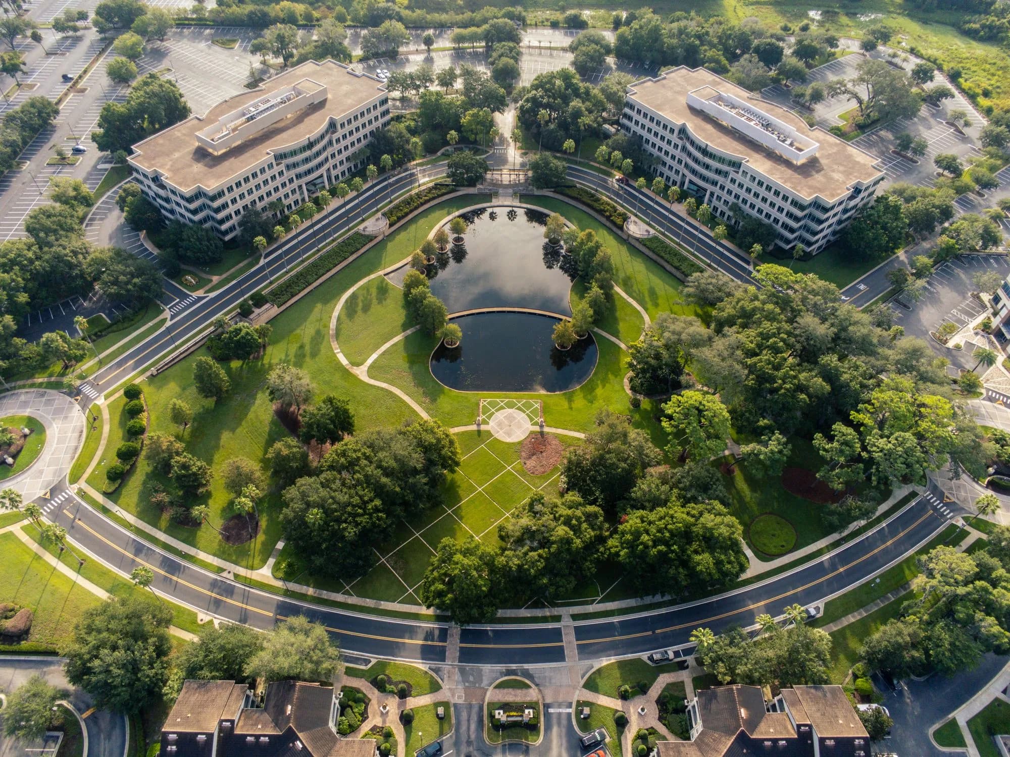 Aerial view of a landscaped office campus with two mid-rise buildings and a pond