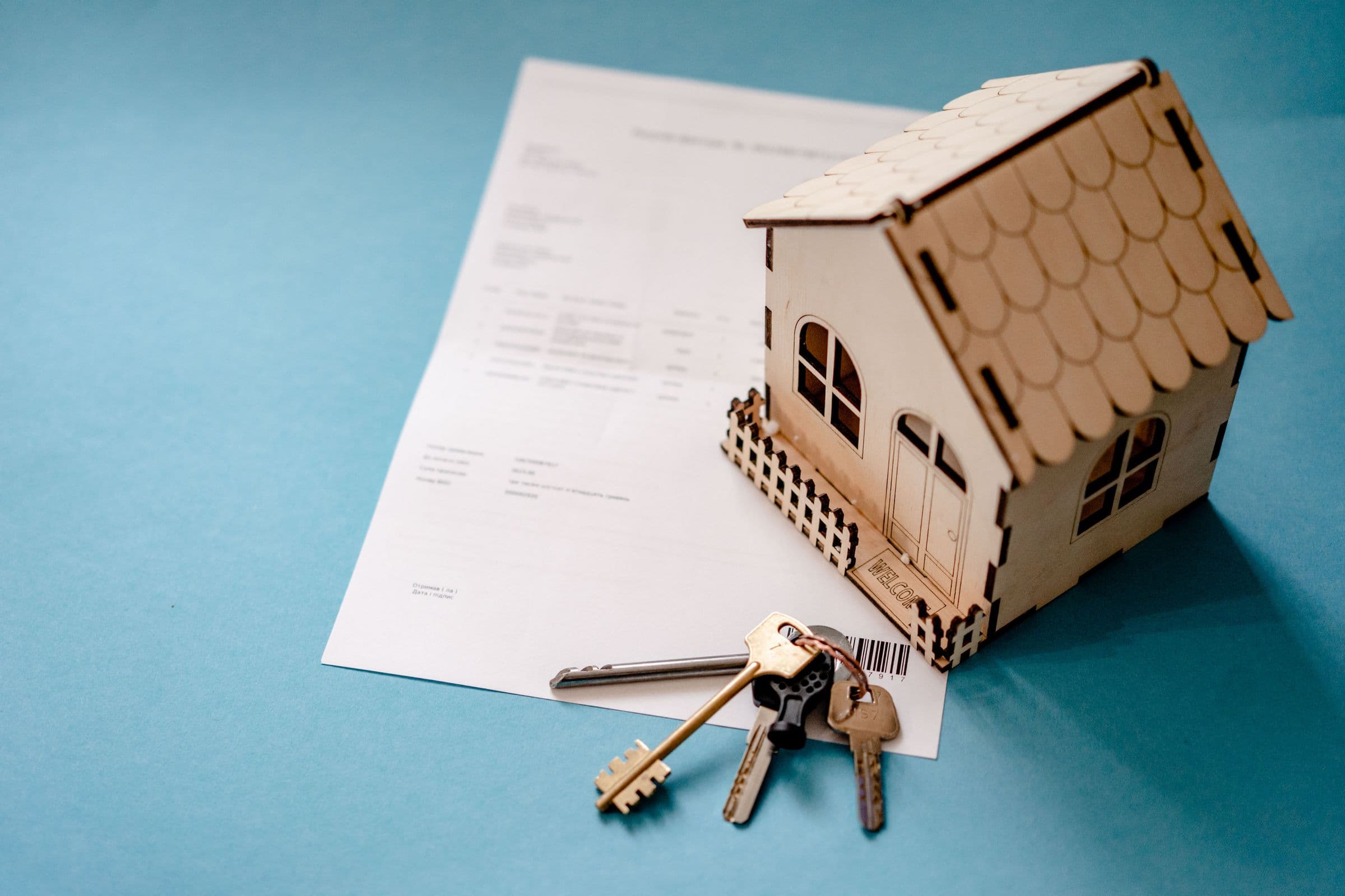 A small wooden model house and a set of keys on a signed contract
