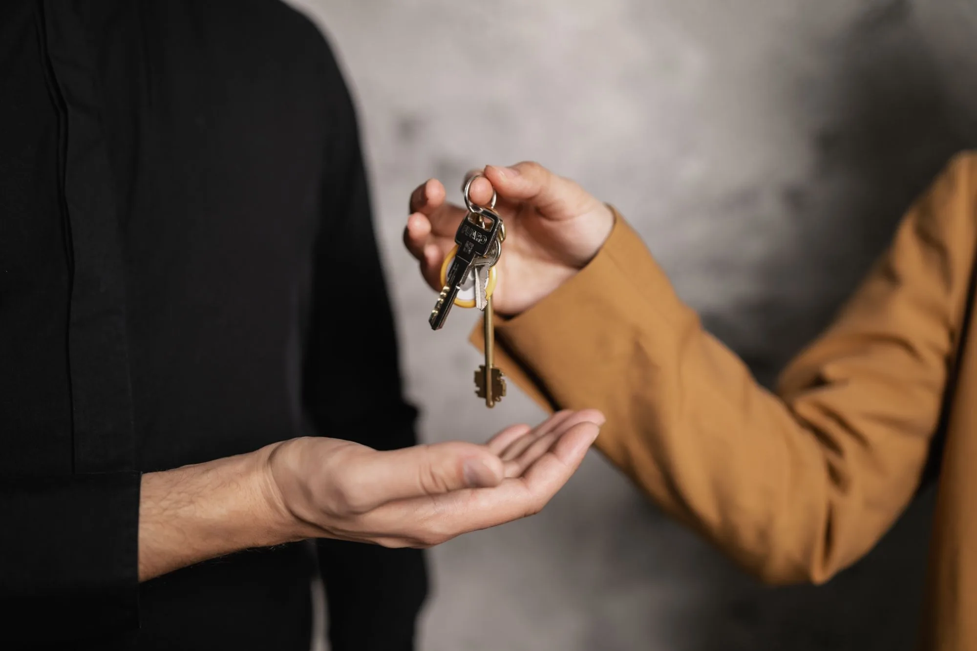 A set of house keys handed into an open palm above a document folder
