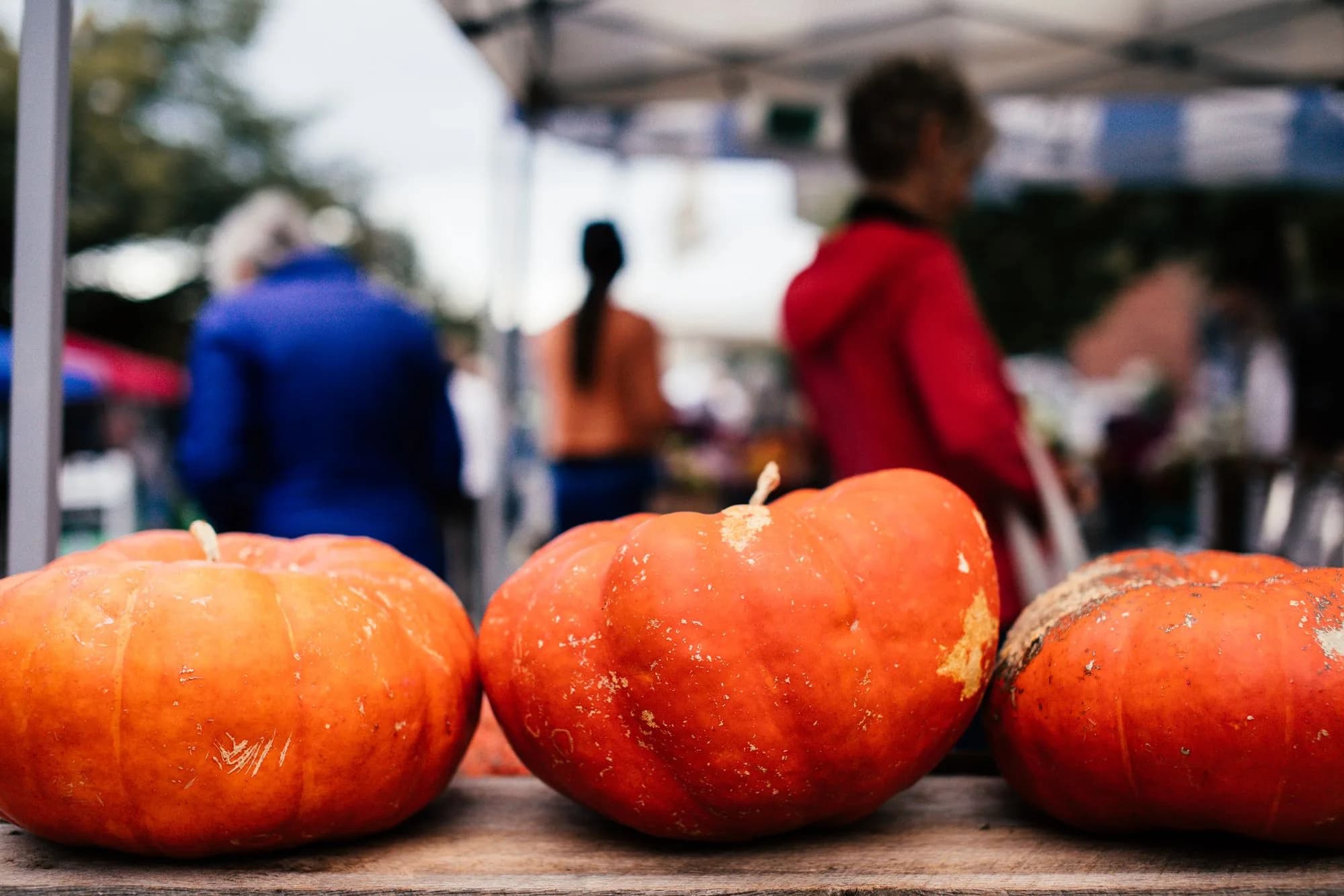Pumpkins on a wooden stall table at an autumn farmers market
